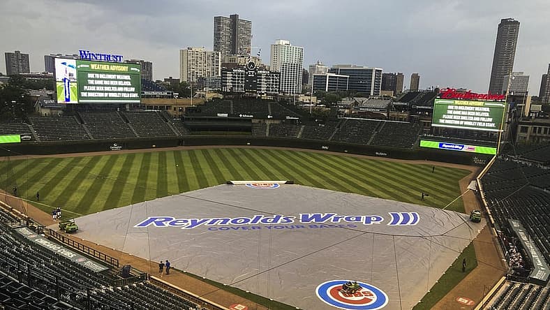 Jul 24, 2021; Chicago, Illinois, USA; Chicago Cubs grounds crew members place the tarp during a rain delay in the ninth inning against the Arizona Diamondbacks at Wrigley Field. Mandatory Credit: Matt Marton-USA TODAY Sports