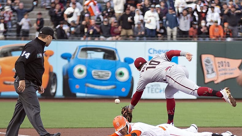 Jul 12, 2022; San Francisco, California, USA; San Francisco Giants third baseman David Villar (bottom) slides safely into third base with a triple ahead of an errant throw to Arizona Diamondbacks third baseman Josh Rojas (10) during the first inning at Oracle Park. Villar was awarded home after the ball went out of play. Mandatory Credit: D. Ross Cameron-USA TODAY Sports