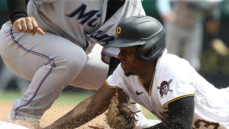 Jul 24, 2022; Pittsburgh, Pennsylvania, USA;  Pittsburgh Pirates third baseman Ke'Bryan Hayes (13) dives back into third base ahead of a tag attempt by Miami Marlins third baseman Willans Astudillo (left) during the sixth inning at PNC Park. Mandatory Credit: Charles LeClaire-USA TODAY Sports