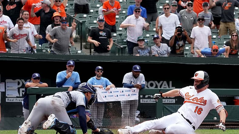 Jul 28, 2022; Baltimore, Maryland, USA; Baltimore Orioles designated hitter Trey Mancini (16) slides in safely for a two-run, inside-the-park home run in the eighth inning against Tampa Bay Rays catcher Rene Pinto (50) at Oriole Park at Camden Yards. Mandatory Credit: Mitch Stringer-USA TODAY Sports