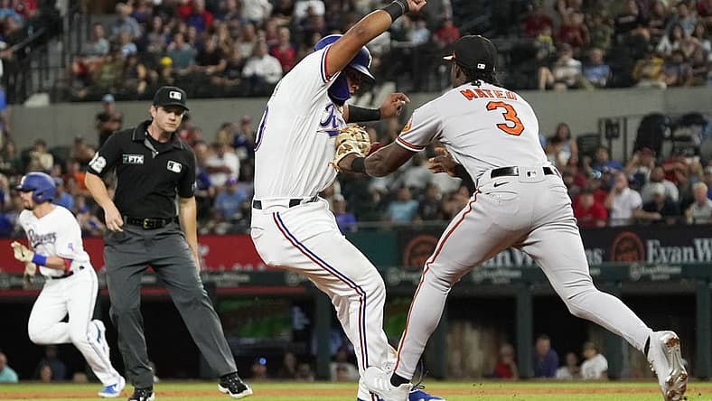Aug 2, 2022; Arlington, Texas, USA; Texas Rangers catcher Meibrys Viloria (60) is tagged out by Baltimore Orioles shortstop Jorge Mateo (3) after being caught in a run down between second and third base during the second inning at Globe Life Field. Mandatory Credit: Raymond Carlin III-USA TODAY Sports