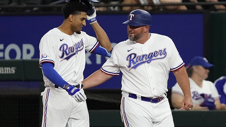 Aug 4, 2022; Arlington, Texas, USA; Texas Rangers left fielder Bubba Thompson (65) is congratulated by first base coach Corey Ragsdale (64) after bunting for his first MLB hit during the seventh inning against the Chicago White Sox at Globe Life Field. Mandatory Credit: Raymond Carlin III-USA TODAY Sports