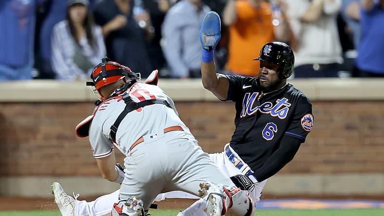 Aug 12, 2022; New York City, New York, USA; Philadelphia Phillies catcher J.T. Realmuto (10) tags out New York Mets right fielder Starling Marte (6) trying to score on a fly ball out by pinch hitter Daniel Vogelbach (not pictured) during the ninth inning at Citi Field. Mandatory Credit: Brad Penner-USA TODAY Sports