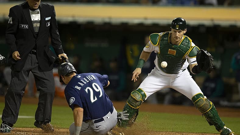 Aug 19, 2022; Oakland, California, USA; Seattle Mariners catcher Cal Raleigh (29) slides safely home ahead of the relay to Oakland Athletics catcher Sean Murphy (12) during the eighth inning at RingCentral Coliseum. Mandatory Credit: D. Ross Cameron-USA TODAY Sports