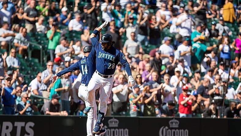 Sep 7, 2022; Seattle, Washington, USA;  Seattle Mariners third baseman Eugenio Suarez (28) celebrates with third base coach Manny Acta (14) after hitting a two run home run for his 1,000th career hit, against the Chicago White Sox during the third inning at T-Mobile Park. Mandatory Credit: Lindsey Wasson-USA TODAY Sports