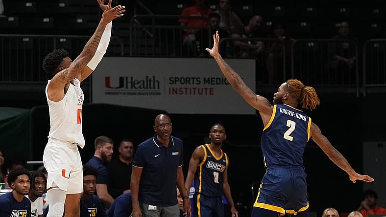 Nov 11, 2022; Coral Gables, Florida, USA; Miami Hurricanes guard Jordan Miller (11) attempts a three point shot over UNC Greensboro Spartans forward Mikeal Brown-Jones (2) during the first half at Watsco Center. Mandatory Credit: Jasen Vinlove-USA TODAY Sports