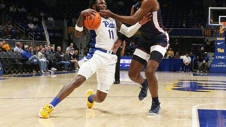 Nov 22, 2022; Pittsburgh, Pennsylvania, USA;  Pittsburgh Panthers guard Jamarius Burton (11) dribbles the ball against Fairleigh Dickinson Knights forward Ansley Almonor (right) during the first half at the Petersen Events Center. Mandatory Credit: Charles LeClaire-USA TODAY Sports