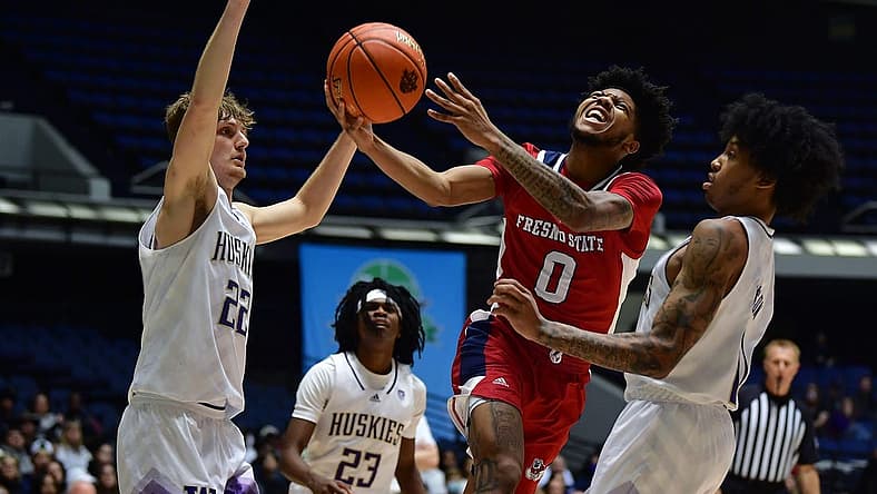 Nov 23, 2022; Anaheim, California, USA; Fresno State Bulldogs guard Donavan Yap (0) moves to the basket against Washington Huskies guard Cole Bajema (22) forward Langston Wilson (13) during the first half at Anaheim Convention Center. Mandatory Credit: Gary A. Vasquez-USA TODAY Sports
