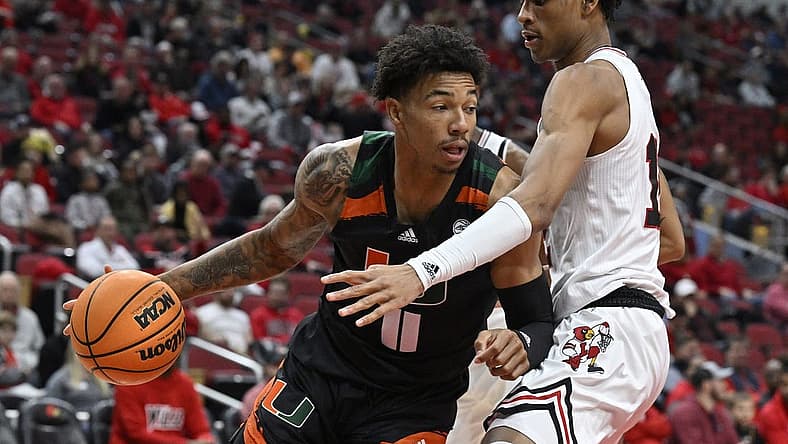 Dec 4, 2022; Louisville, Kentucky, USA; Miami (Fl) Hurricanes guard Jordan Miller (11) dribbles against Louisville Cardinals forward JJ Traynor (12) during the first half at KFC Yum! Center. Mandatory Credit: Jamie Rhodes-USA TODAY Sports