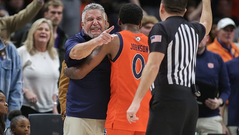 Dec 10, 2022; Atlanta, Georgia, USA; Auburn Tigers head coach Bruce Pearl is held back by guard K.D. Johnson (0) after a technical foul in the second half against the Memphis Tigers at State Farm Arena. Mandatory Credit: Brett Davis-USA TODAY Sports