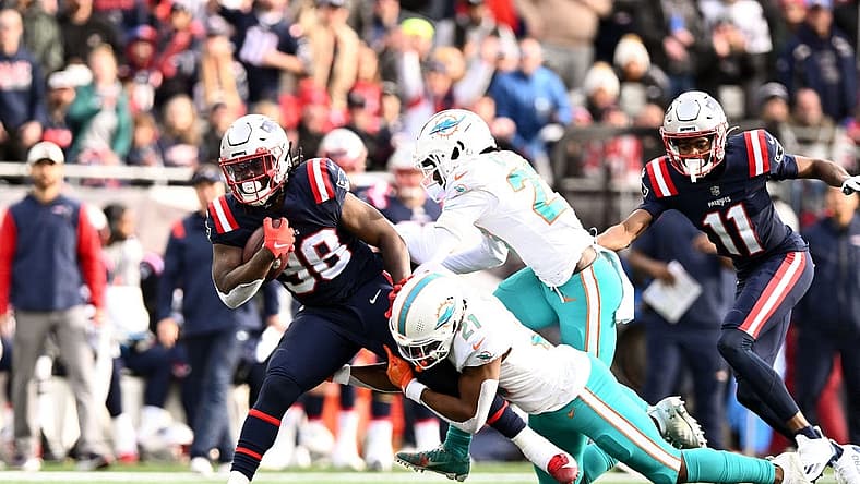 Jan 1, 2023; Foxborough, Massachusetts, USA; Miami Dolphins safety Eric Rowe (21) takles New England Patriots running back Rhamondre Stevenson (38) during the first half at Gillette Stadium. Mandatory Credit: Brian Fluharty-USA TODAY Sports