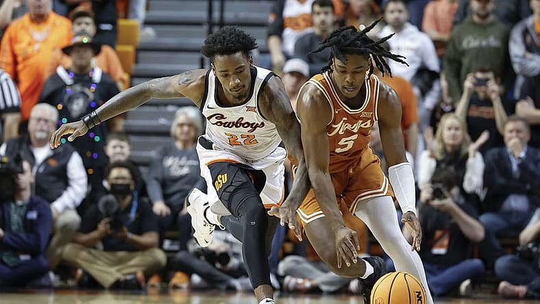 Jan 7, 2023; Stillwater, Oklahoma, USA; Oklahoma State Cowboys forward Kalib Boone (22) and Texas Longhorns guard Marcus Carr (5) reach for a loose ball during the first half at Gallagher-Iba Arena. Mandatory Credit: Alonzo Adams-USA TODAY Sports