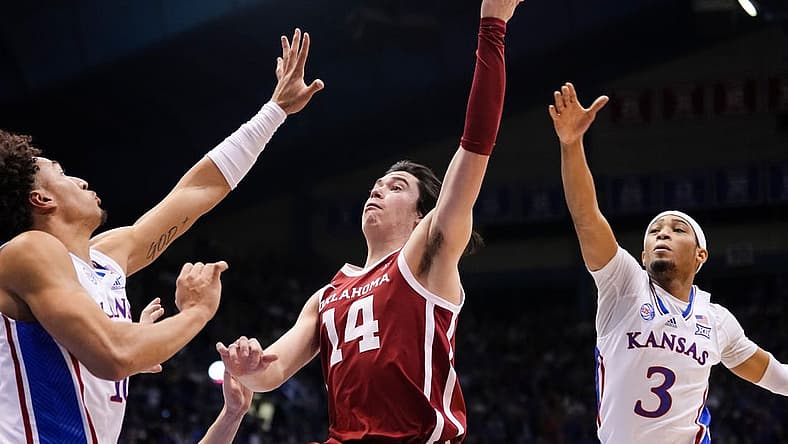 Jan 10, 2023; Lawrence, Kansas, USA; Oklahoma Sooners guard Bijan Cortes (14) shoots against Kansas Jayhawks forward Jalen Wilson (10) and guard Dajuan Harris Jr. (3) during the first half at Allen Fieldhouse. Mandatory Credit: Jay Biggerstaff-USA TODAY Sports