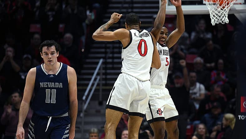 Jan 10, 2023; San Diego, California, USA; San Diego State Aztecs forward Keshad Johnson (0) and guard Lamont Butler (5) celebrate as Nevada Wolf Pack forward Nick Davidson (11) looks on during the first half at Viejas Arena. Mandatory Credit: Orlando Ramirez-USA TODAY Sports