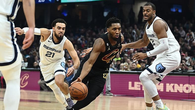 Feb 2, 2023; Cleveland, Ohio, USA; Cleveland Cavaliers guard Donovan Mitchell (45) drives to the basket between Memphis Grizzlies guard Tyus Jones (21) and forward Xavier Tillman (2) during the first half at Rocket Mortgage FieldHouse. Mandatory Credit: Ken Blaze-USA TODAY Sports