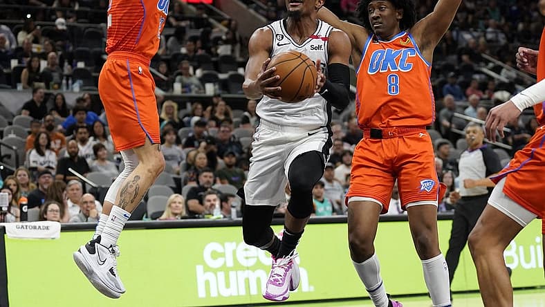 Mar 12, 2023; San Antonio, Texas, USA; San Antonio Spurs guard Devonte' Graham (4) drives to the basket between Oklahoma City Thunder guard Josh Giddey (3) and forward Jalen Williams (8) during the first half at AT&T Center. Mandatory Credit: Scott Wachter-USA TODAY Sports