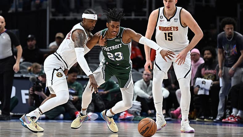 Mar 16, 2023; Detroit, Michigan, USA; Denver Nuggets guard Kentavious Caldwell-Pope (5) (left) knocks the ball away from Detroit Pistons guard Jaden Ivey (23) as Denver Nuggets center Nikola Jokic (15) watches in the first quarter at Little Caesars Arena. Mandatory Credit: Lon Horwedel-USA TODAY Sports