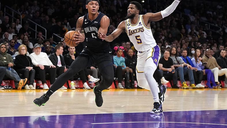 Mar 19, 2023; Los Angeles, California, USA; Orlando Magic forward Paolo Banchero (left) dribbles the ball against Los Angeles Lakers guard Malik Beasley in the first half at Crypto.com Arena. Mandatory Credit: Kirby Lee-USA TODAY Sports