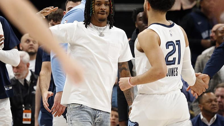 Mar 20, 2023; Memphis, Tennessee, USA; Memphis Grizzlies guard Ja Morant (left) reacts with guard Tyus Jones (21) during a timeout during the second half against the Dallas Mavericks at FedExForum. Mandatory Credit: Petre Thomas-USA TODAY Sports