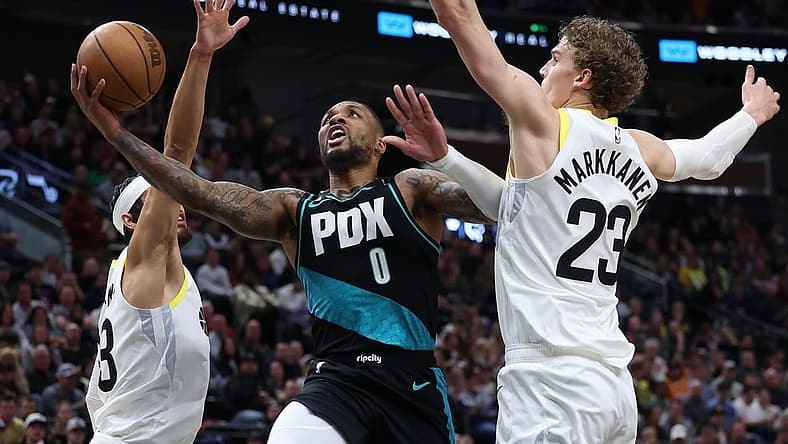 Mar 22, 2023; Salt Lake City, Utah, USA; Portland Trail Blazers guard Damian Lillard (0) drives between Utah Jazz guard Johnny Juzang (33) and forward Lauri Markkanen (23) in the second quarter at Vivint Arena. Mandatory Credit: Rob Gray-USA TODAY Sports