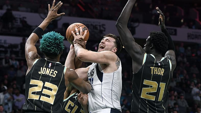 Mar 26, 2023; Charlotte, North Carolina, USA; Dallas Mavericks guard Luka Doncic (77) shoots as he is defended by Charlotte Hornets forward center Kai Jones (23) and forward JT Thor (21) during the first half at the Spectrum Center. Mandatory Credit: Sam Sharpe-USA TODAY Sports