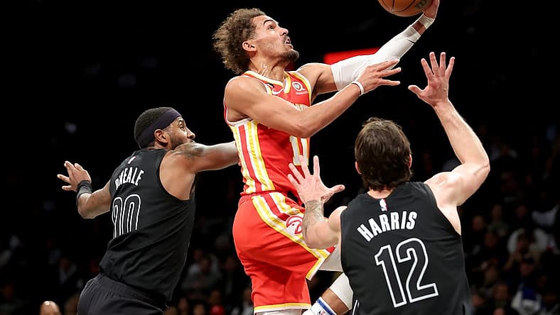 Mar 31, 2023; Brooklyn, New York, USA; Atlanta Hawks guard Trae Young (11) drives to the basket against Brooklyn Nets forwards Royce O'Neale (00) and Joe Harris (12) during the second quarter at Barclays Center. Mandatory Credit: Brad Penner-USA TODAY Sports