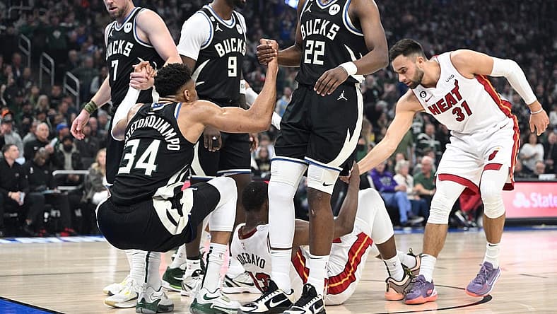 Apr 16, 2023; Milwaukee, Wisconsin, USA; Milwaukee Bucks forward Giannis Antetokounmpo (34) is helped up after a collision in the first half against Miami Heat center Bam Adebayo (13) during game one of the 2023 NBA Playoffs at Fiserv Forum. Mandatory Credit: Michael McLoone-USA TODAY Sports