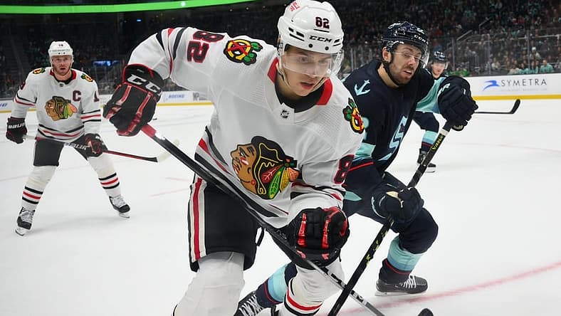 Apr 8, 2023; Seattle, Washington, USA; Chicago Blackhawks defenseman Caleb Jones (82) and Seattle Kraken right wing Oliver Bjorkstrand (22) fight for the puck during the second period at Climate Pledge Arena. Mandatory Credit: Steven Bisig-USA TODAY Sports