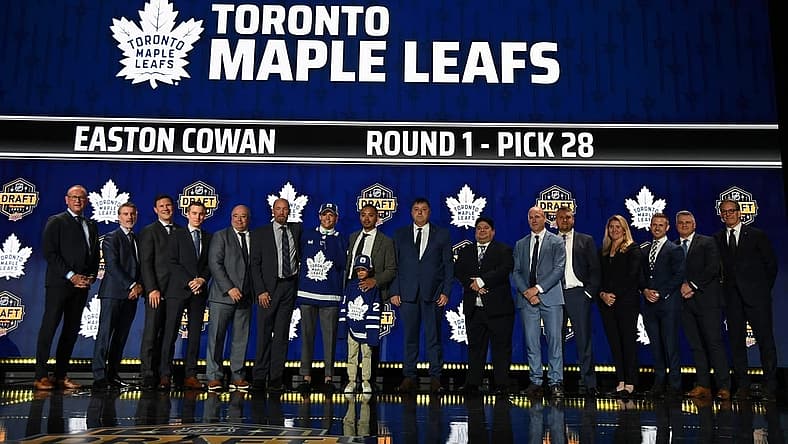 Jun 28, 2023; Nashville, Tennessee, USA; Toronto Maple Leafs draft pick Easton Cowan stands with Leafs staff after being selected with the twenty eighth pick in round one of the 2023 NHL Draft at Bridgestone Arena. Mandatory Credit: Christopher Hanewinckel-USA TODAY Sports