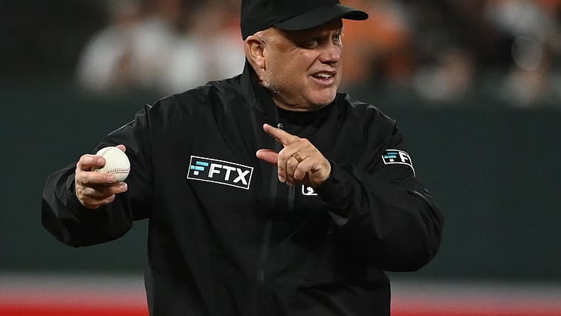 Apr 12, 2022; Baltimore, Maryland, USA; Umpire Brian O'Nora (7) signals while holding a baseball during the game between the Baltimore Orioles and the Milwaukee Brewers at Oriole Park at Camden Yards. Mandatory Credit: Tommy Gilligan-USA TODAY Sports