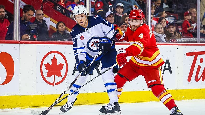 Oct 2, 2023; Calgary, Alberta, CAN; Winnipeg Jets center Mason Appleton (22) and Calgary Flames defenseman Rasmus Andersson (4) battle for the puck during the first period at Scotiabank Saddledome. Mandatory Credit: Sergei Belski-USA TODAY Sports