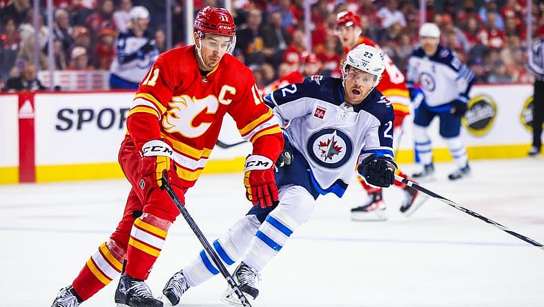Oct 11, 2023; Calgary, Alberta, CAN; Calgary Flames center Mikael Backlund (11) controls the puck against Winnipeg Jets center Mason Appleton (22) during the first period at Scotiabank Saddledome. Mandatory Credit: Sergei Belski-USA TODAY Sports