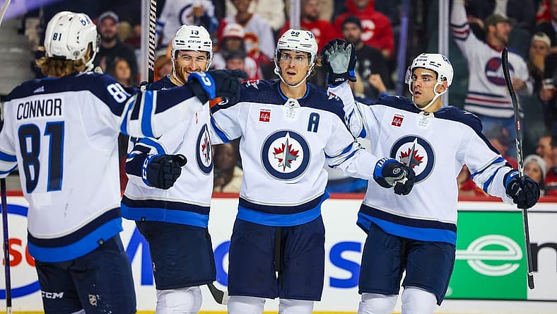 Oct 11, 2023; Calgary, Alberta, CAN; Winnipeg Jets center Mark Scheifele (55) celebrates his goal with teammates against the Calgary Flames during the third period at Scotiabank Saddledome. Mandatory Credit: Sergei Belski-USA TODAY Sports