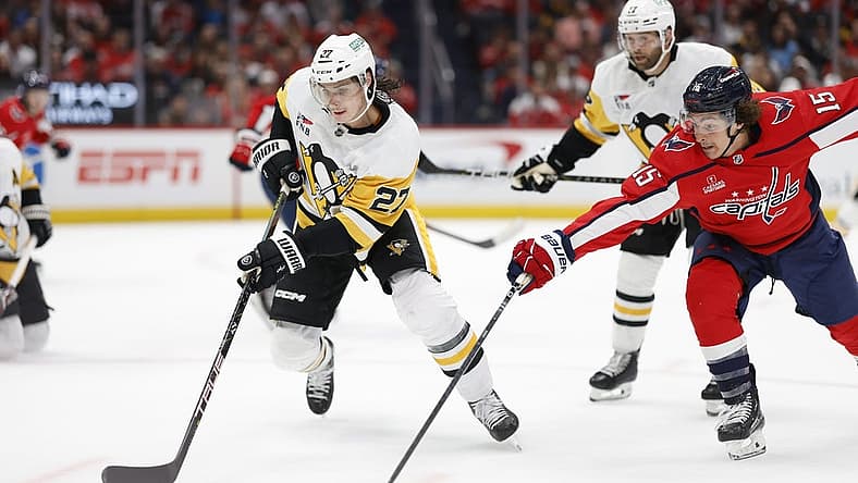 Oct 13, 2023; Washington, District of Columbia, USA; Pittsburgh Penguins defenseman Ryan Graves (27) skates with the puck as Washington Capitals left wing Sonny Milano (15) defends in the first period at Capital One Arena. Mandatory Credit: Geoff Burke-USA TODAY Sports