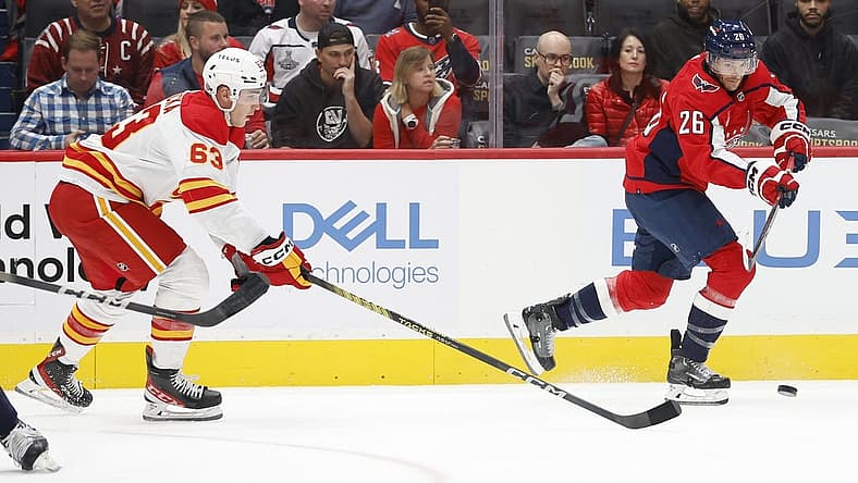Oct 16, 2023; Washington, District of Columbia, USA; Washington Capitals right wing Nic Dowd (26) passes the puck as Calgary Flames center Adam Ruzicka (63) chases in the first period at Capital One Arena. Mandatory Credit: Geoff Burke-USA TODAY Sports