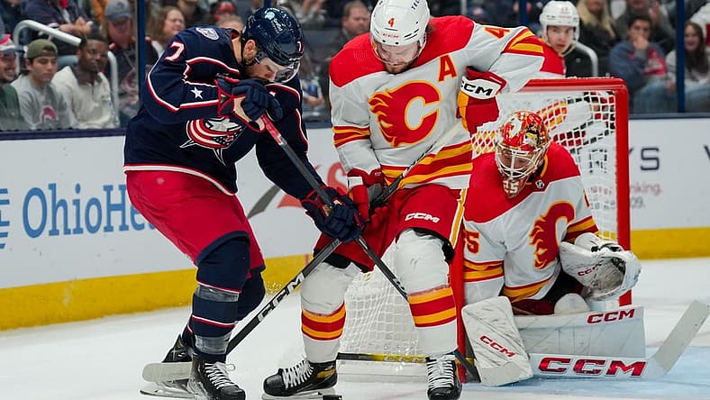 Oct 20, 2023; Columbus, Ohio, USA; Columbus Blue Jackets center Sean Kuraly (7) battles for the puck against Calgary Flames defenseman Rasmus Andersson (4) in the first period at Nationwide Arena. Mandatory Credit: Aaron Doster-USA TODAY Sports