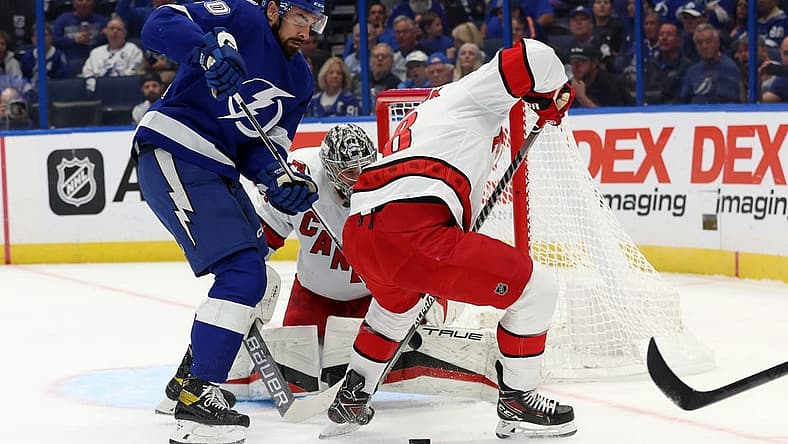 Oct 24, 2023; Tampa, Florida, USA; Tampa Bay Lightning left wing Nicholas Paul (20) shoots as Carolina Hurricanes left wing Jordan Martinook (48) defends during the first period at Amalie Arena. Mandatory Credit: Kim Klement Neitzel-USA TODAY Sports