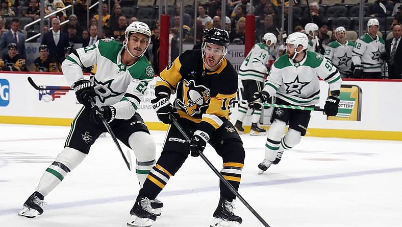 Oct 24, 2023; Pittsburgh, Pennsylvania, USA; Pittsburgh Penguins right wing Reilly Smith (19) carries the puck into the offensive zone ahead of Dallas Stars left wing Mason Marchment (27) during the first period at PPG Paints Arena. Mandatory Credit: Charles LeClaire-USA TODAY Sports