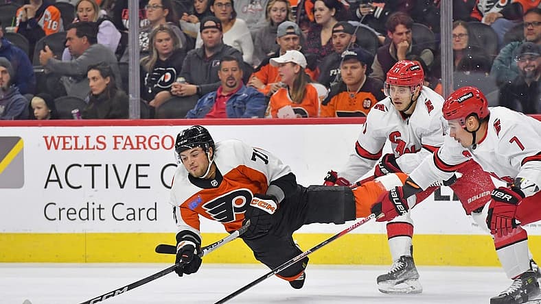 Oct 30, 2023; Philadelphia, Pennsylvania, USA; Philadelphia Flyers right wing Tyson Foerster (71) passes the puck while being upended by Carolina Hurricanes right wing Jesper Fast (71) and defenseman Dmitry Orlov (7) during the first period at Wells Fargo Center. Mandatory Credit: Eric Hartline-USA TODAY Sports