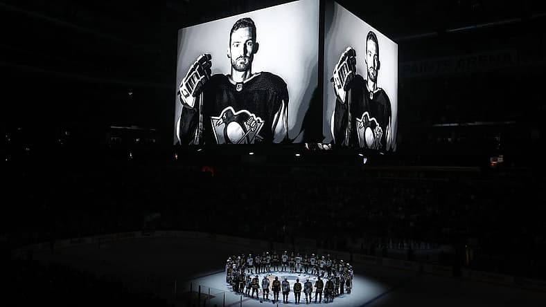 Oct 30, 2023; Pittsburgh, Pennsylvania, USA; Members of the Anaheim Ducks and the Pittsburgh Penguins stand at center ice for a moment of silence at the PPG Paints Arena to honor former Penguin forward Adam Johnson (on scoreboard) who was tragically killed in a hockey related accident in Europe. Mandatory Credit: Charles LeClaire-USA TODAY Sports