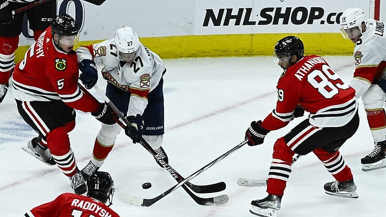 Nov 4, 2023; Chicago, Illinois, USA;  Chicago Blackhawks defenseman Connor Murphy (5) and Chicago Blackhawks center Andreas Athanasiou (89) fight for the puck with Florida Panthers center Eetu Luostarinen (27) during the second period at the United Center. Mandatory Credit: Matt Marton-USA TODAY Sports