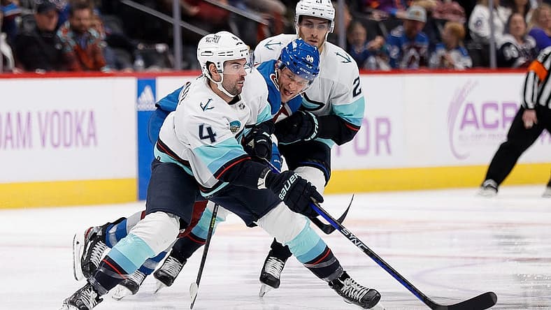 Nov 9, 2023; Denver, Colorado, USA; Seattle Kraken defenseman Justin Schultz (4) controls the puck under pressure from Colorado Avalanche right wing Mikko Rantanen (96) as center Alex Wennberg (21) looks on in the second period at Ball Arena. Mandatory Credit: Isaiah J. Downing-USA TODAY Sports