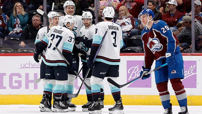 Nov 9, 2023; Denver, Colorado, USA; Seattle Kraken right wing Oliver Bjorkstrand (22) celebrates his goal with center Yanni Gourde (37) and right wing Eeli Tolvanen (20) and defenseman Jamie Oleksiak (24) and defenseman Will Borgen (3) as Colorado Avalanche center Nathan MacKinnon (29) skates by in the second period at Ball Arena. Mandatory Credit: Isaiah J. Downing-USA TODAY Sports