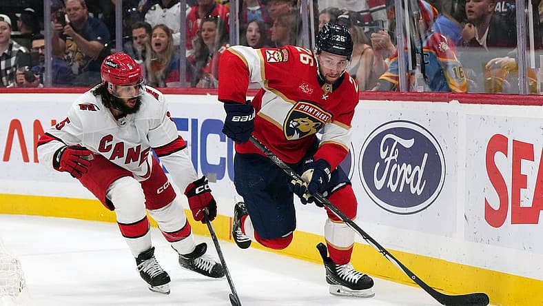 Nov 10, 2023; Sunrise, Florida, USA; Florida Panthers defenseman Uvis Balinskis (26) controls the puck away from Carolina Hurricanes defenseman Jalen Chatfield (5) during the second period at Amerant Bank Arena. Mandatory Credit: Jasen Vinlove-USA TODAY Sports
