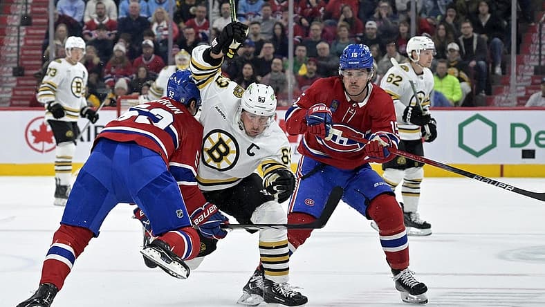 Nov 11, 2023; Montreal, Quebec, CAN; Boston Bruins forward Brad Marchand (63) splits Montreal Canadiens defenseman Justin Barron (52) and teammate forward Alex Newhook (15) during the first period at the Bell Centre. Mandatory Credit: Eric Bolte-USA TODAY Sports