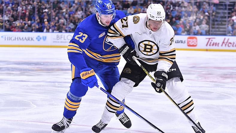 Nov 14, 2023; Buffalo, New York, USA; Boston Bruins defenseman Hampus Lindholm (27) and Buffalo Sabres defenseman Mattias Samuelsson (23) battle for the puck in the first period at KeyBank Center. Mandatory Credit: Mark Konezny-USA TODAY Sports