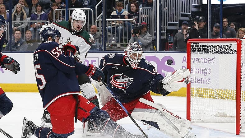 Nov 16, 2023; Columbus, Ohio, USA; Columbus Blue Jackets goalie Elvis Merzlikins (90) deflects the puck over the net as Arizona Coyotes left wing Matias Maccelli (63) awaits a rebound during the first period at Nationwide Arena. Mandatory Credit: Russell LaBounty-USA TODAY Sports