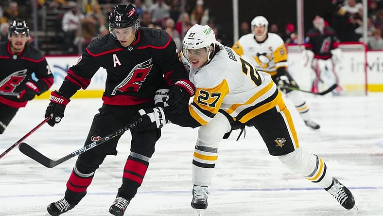 Nov 18, 2023; Raleigh, North Carolina, USA; Carolina Hurricanes center Sebastian Aho (20) tries to control the puck against Pittsburgh Penguins defenseman Ryan Graves (27) during the first period at PNC Arena. Mandatory Credit: James Guillory-USA TODAY Sports
