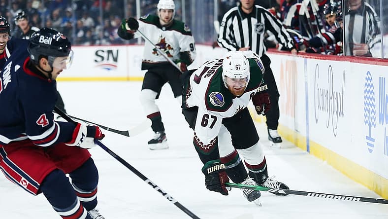 Nov 18, 2023; Winnipeg, Manitoba, CAN; Arizona Coyotes forward Lawson Crouse (67) and Winnipeg Jets defenseman Neal Pionk (4) chase after the puck during the first period at Canada Life Centre. Mandatory Credit: Terrence Lee-USA TODAY Sports