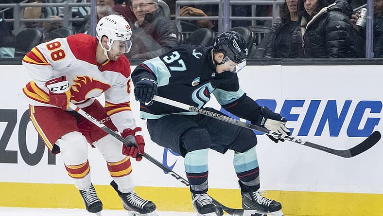 Nov 20, 2023; Seattle, Washington, USA; Seattle Kraken forward Yanni Gourde (37) and Calgary Flames forward Andrew Mangiapane (88) battle for the puck during the first period at Climate Pledge Arena. Mandatory Credit: Stephen Brashear-USA TODAY Sports